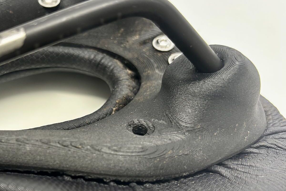 Nahaufnahme eines schwarzen Fahrradsattels mit sichtbarer Befestigung und Schrauben auf der Unterseite.